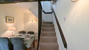 Un coin repas avec une table dressée pour quatre personnes, un escalier et un luminaire fixé au mur.