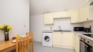 Une cuisine compacte équipée d’un lave-linge, d’un évier et d’un four à micro-ondes.