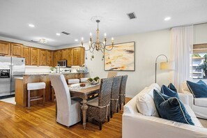 Eine moderne Küche mit Holzschränken, einem Edelstahlkühlschrank und einem Essbereich mit Tisch und Stühlen.