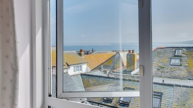 A view from a window overlooking a coastal town with buildings and a clear sky.