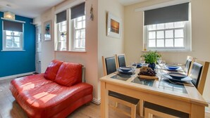 A dining area with a table set for four, a red leather couch, and a window with a view.