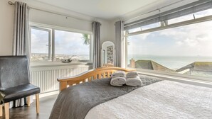 A bedroom with a large bed, a chair, and a view of the sea. - 3 Bed in Newlyn (oc-s33015) (Newlyn)