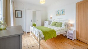 Quarto com cama, mesas de cabeceira, guarda-roupa e luminária suspensa.