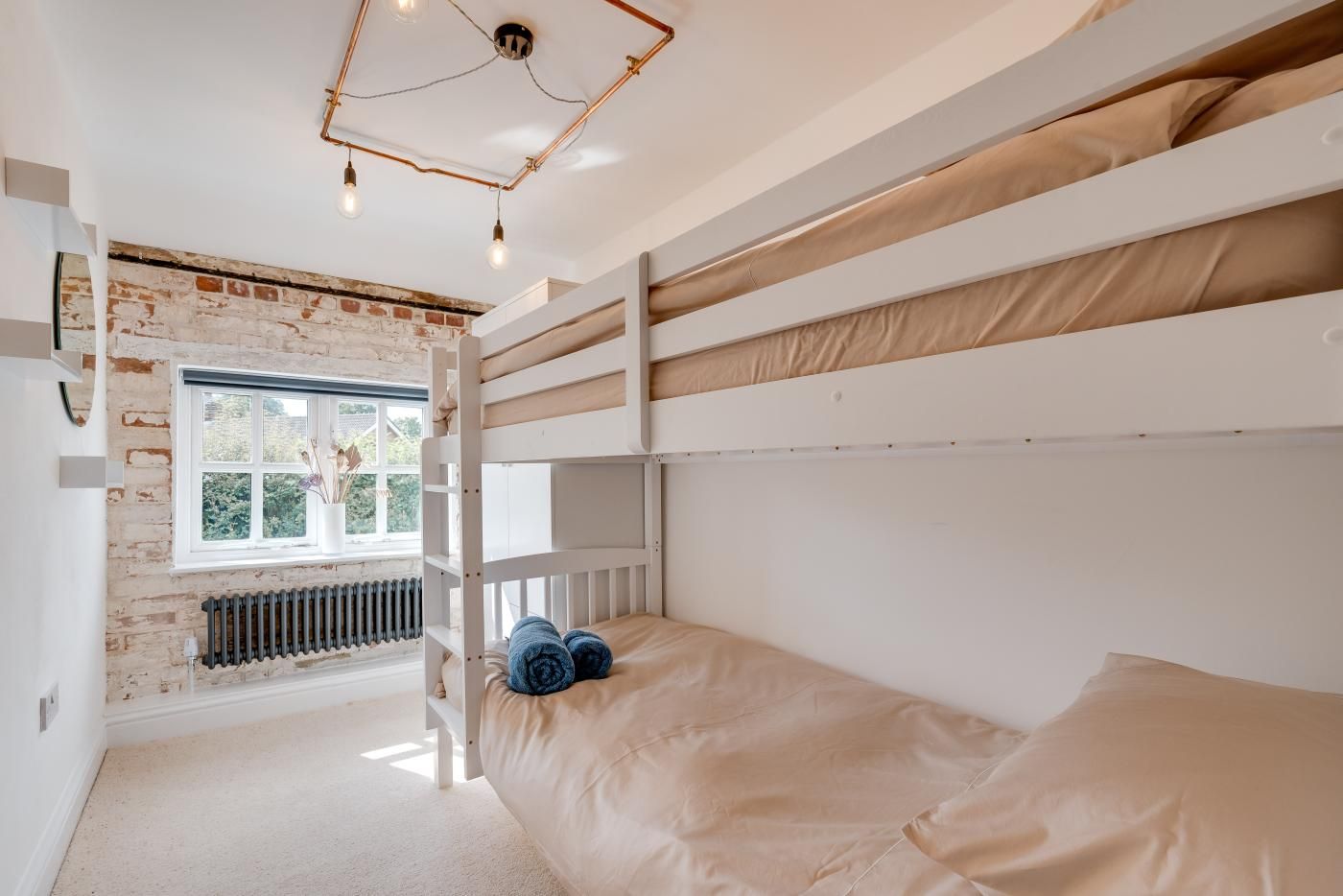 A bunk bed room with a brick wall, a window, and a radiator.