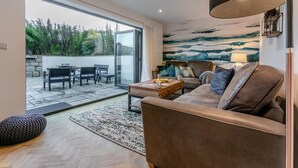 Een moderne woonkamer met een bank, salontafel en uitzicht op een tuin door een glazen deur.