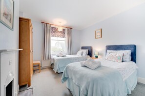 A bedroom with two beds, a wooden wardrobe, a fireplace, and a window with curtains. - 2 Bed in Southwold (oc-kin) (Southwold)