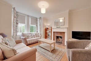 Una sala de estar con sofá, mesa de centro, chimenea y televisión.