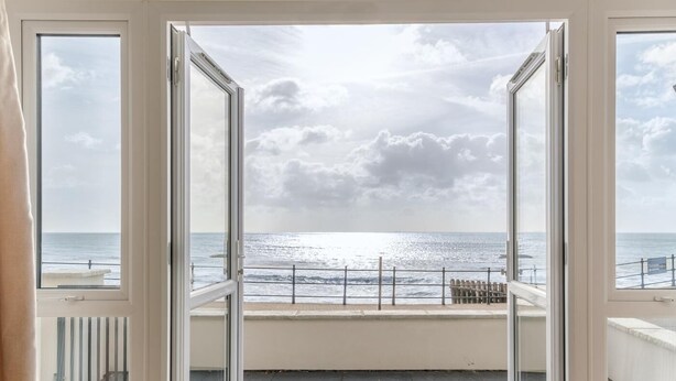 Ein Zimmer mit Meerblick durch offene Glasüren.