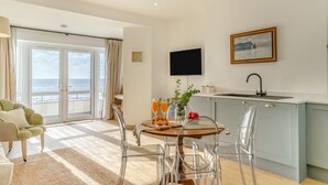 Ein modernes Wohnzimmer mit einem großen Schiebeglasfenster, das auf einen Balkon mit Meerblick führt.
