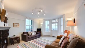 A modern living room with a sofa, armchairs, a TV, and a fireplace. - 1 Bed in Southwold (oc-sl162) (Southwold)