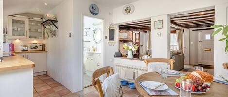 Une cuisine avec un coin repas, une horloge et une vue sur le salon.