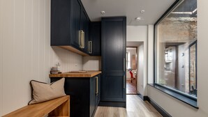 Un couloir étroit avec des meubles sombres, un banc en bois et une grande fenêtre.