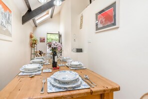 Une table à manger dressée avec des assiettes, des verres et des couverts, un vase rempli de fleurs et une bouteille de vin.
