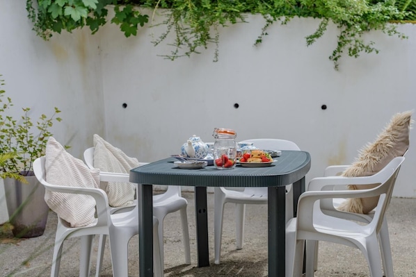 Une table ronde avec des chaises, une théière, un bocal en verre et une assiette remplie de nourriture.