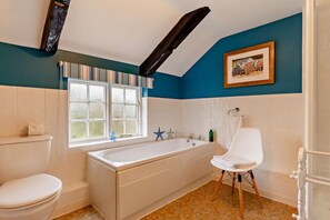 A bathroom with a bathtub, toilet, and a window.