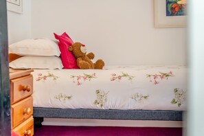A bed with floral bedding, a teddy bear, and a wooden dresser with drawers. - 4 Bed in Two Waters Foot (oc-f27331) (Warleggan)