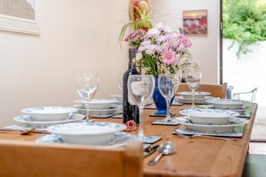 Een eettafel gedekt met borden, glazen en een bloevas.