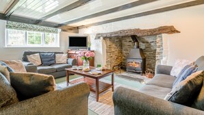A cozy living room with a stone fireplace, comfortable seating, and a television.