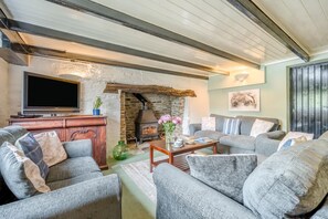 A cozy living room with a stone fireplace, a flat-screen TV, and comfortable seating.