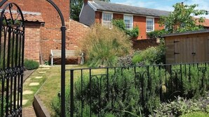 A brick house with a tiled roof, a wooden shed, and a metal gate. - 2 Bed in Woodbridge (oc-csn2) (Woodbridge)