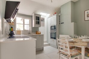 A compact kitchen with white cabinets, a built-in oven, and a dining area with a table set for four.