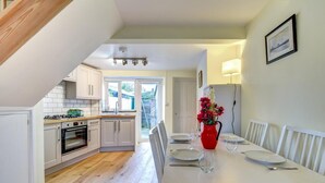 Una cucina moderna con mobili bianchi, un piano di lavoro in legno e un'area pranzo con un tavolo bianco apparecchiato per due persone.