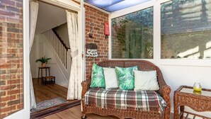 A wicker sofa with a plaid blanket, a small table with a glass, and a potted plant. - 2 Bed in Friston (oc-lcq) (Friston)