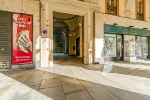 A building entrance with a tiled floor, a red advertisement, and a shop with glass windows. - GuestHost - Charming 85 sqm apartment, ideal for groups or families of up to 5 guests, located on the third floor of a historic building with an elevator (NOT suitable for guests with disabilities).The property is located in an elegant area, right in the (Turin)
