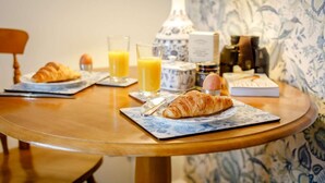 Ein Frühstückstisch mit Croissants, Orangensaft und einer Lampe auf einer Holztischplatte.