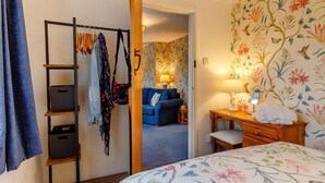 Ein Schlafzimmer mit einem Bett, einem Holzschrank, einem blauen Sofa und floraler Tapete.