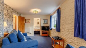 Ein gemütliches Wohnzimmer mit einem blauen Sofa, einem kleinen Holztisch und einem Fernseher.