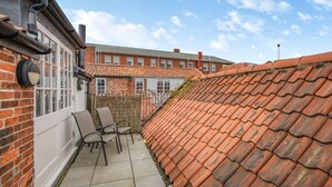 A courtyard with a tiled roof, a brick wall, and a white door. - 3 Bed in Southwold (oc-vth) (Southwold)