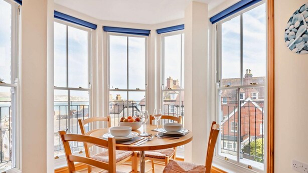 Un coin repas avec une table ronde, quatre chaises et une vue sur la ville grâce à de grandes fenêtres.