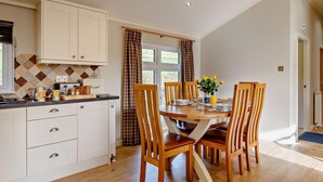 A kitchen with white cabinets, a dining table with chairs, and a window with curtains.