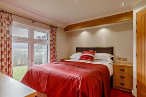 A bedroom with a bed, bedside table, and a view of the outdoors.