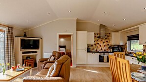 A living room with a sofa, TV, and dining area with a table and chairs.