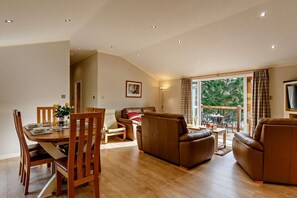 A spacious living area with a dining table, leather sofas, and a large window offering a view of greenery. - 3 Bed in Two Waters Foot (oc-m27335) (Broadoak)