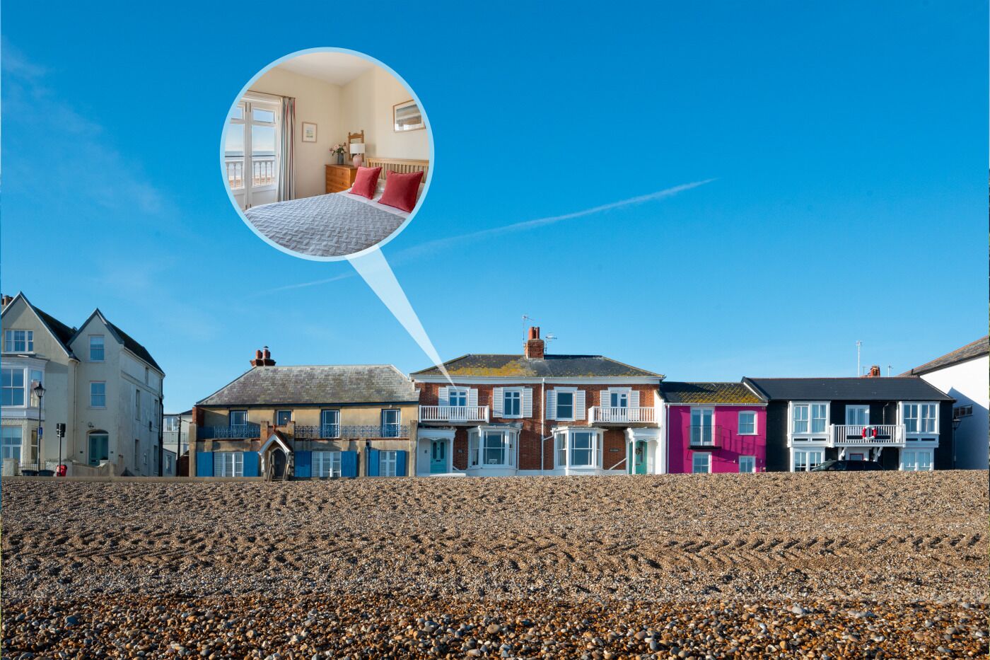 A coastal property with a pebbled beach, a variety of colorful houses, and a magnified view of a bedroom with a bed, pillows, and a nightstand.
