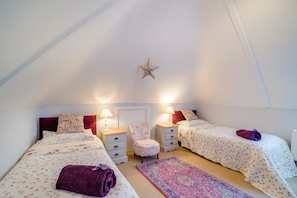 Ein Schlafzimmer mit zwei Betten, einem Sessel, einer Sternen-Dekoration und einem gemusterten Teppich.
