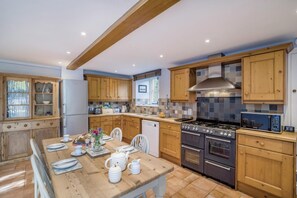 A kitchen with wooden cabinets, a dining table set with white dishes, and a stove.