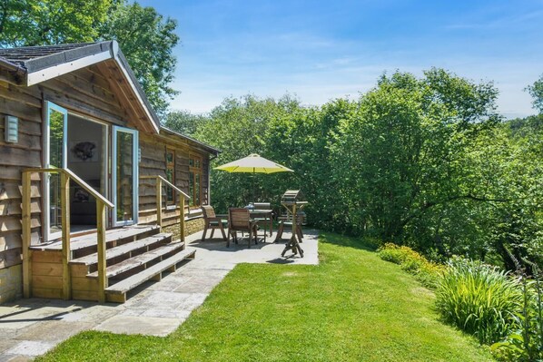 Une cabane en rondins avec un porche, un espace salon extérieur et un jardin.