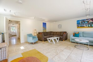 Un salon avec un canapé marron, un fauteuil bleu, une table basse blanche et un autre canapé bleu.