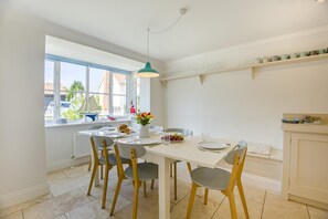A dining area with a table set for four, chairs, a pendant light, and a window with a view of the outside. - 4 Bed in Friston (oc-colu) (Friston)