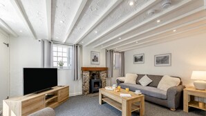 Ein modernes Wohnzimmer mit Flachbildfernseher, Kamin aus Stein, einer Couch und einem Couchtisch.