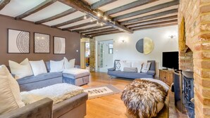 A spacious living room with exposed wooden beams, a fireplace, and two sofas with decorative pillows. - 6 Bed in Foulsham (oc-t33038) (Foulsham)