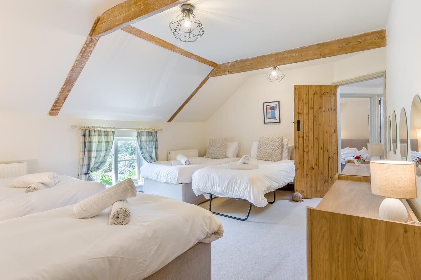 Une chambre avec deux lits, un plafond en bois, une fenêtre avec des rideaux et une lampe de chevet.