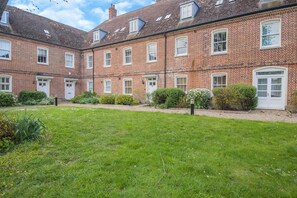 A brick building with multiple windows and doors, surrounded by a well-maintained lawn and small shrubs. - 2 Bed in Blythburgh (oc-wag2) (Bulcamp)