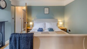 Habitación de hotel con una cama, lámparas de noche, un reloj y un cuadro en la pared.