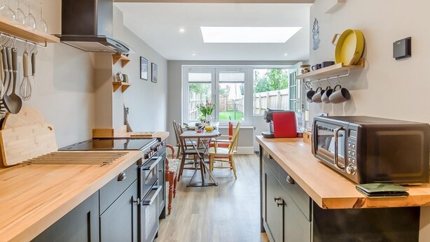 Una cocina moderna con comedor, encimeras de madera y vistas al exterior.