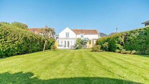 Een verzorgd gazon met een huis op de achtergrond.